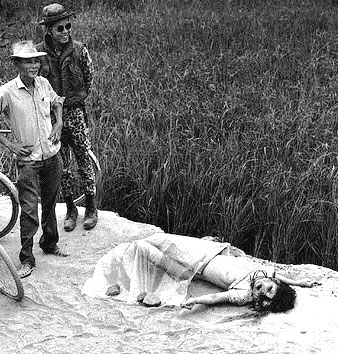 Vietnam photograph. The woman has been raped and murdered. The men smile and pose for the photographer.